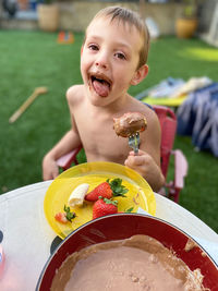 Boy having food having food while sitting in yard