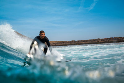 Man surfing on sea against sky