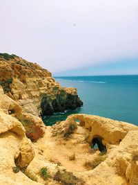 Rock formation on beach against sky