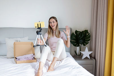 Portrait of woman sitting on bed at home