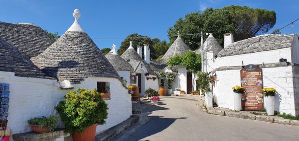 Street amidst trees and buildings against sky
