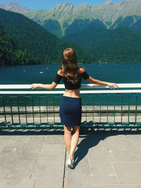 Rear view of young woman standing by railing