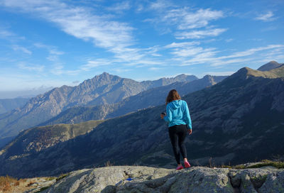 Rear view of woman standing against mountain range