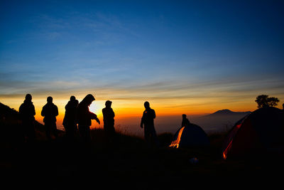 Silhouette people on mountain against sky during sunset