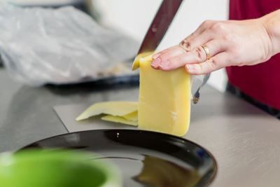 Slices of cheese on cutting board, woman cooking sandwiches for breakfast