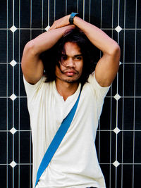 Young man looking away against metal grate