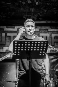 Male singer gesturing while singing on stage during concert at night