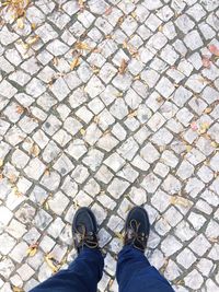 Low section of man wearing shoes standing on cobbled street during autumn