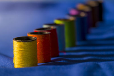 Close-up of colorful spools arranged in row on blue fabric