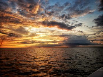 Scenic view of sea against dramatic sky during sunset