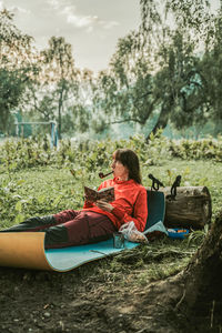 Side view of woman sitting on land