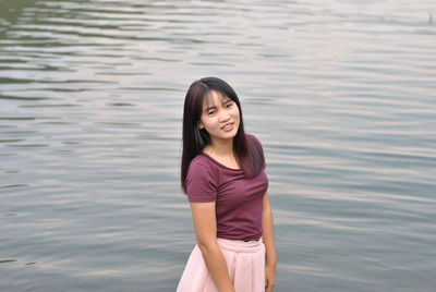 Portrait of smiling young woman standing in water