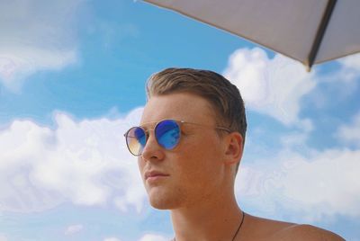 Low angle portrait of man wearing sunglasses against sky