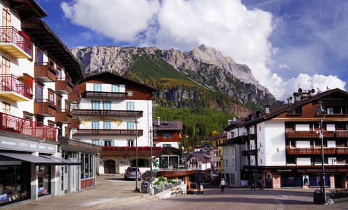 Road by buildings in town against sky