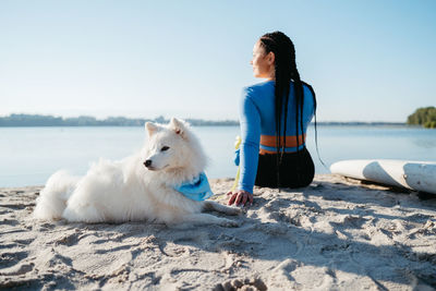 Woman with locs sitting on the beach of city lake with her best friend