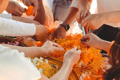 Friends making floral garlands during wedding ceremony