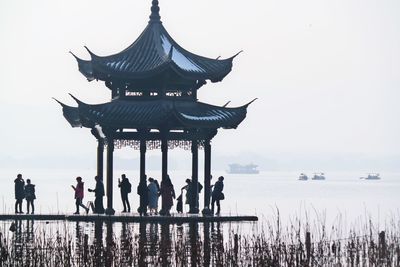 People in lake against clear sky