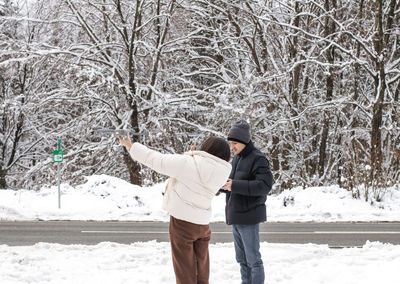 A young couple launches a drone in the winter forest.