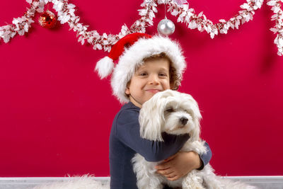 Boy with santa claus hat hugging his doggy