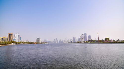 Scenic view of river by buildings against clear sky