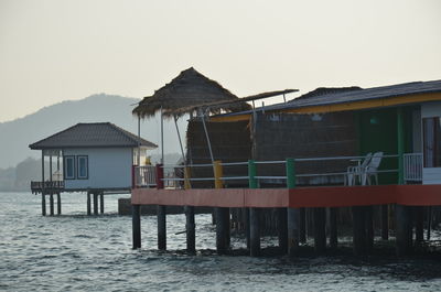 Stilt house by sea against clear sky