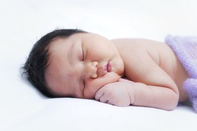 Close-up of baby girl lying on bed