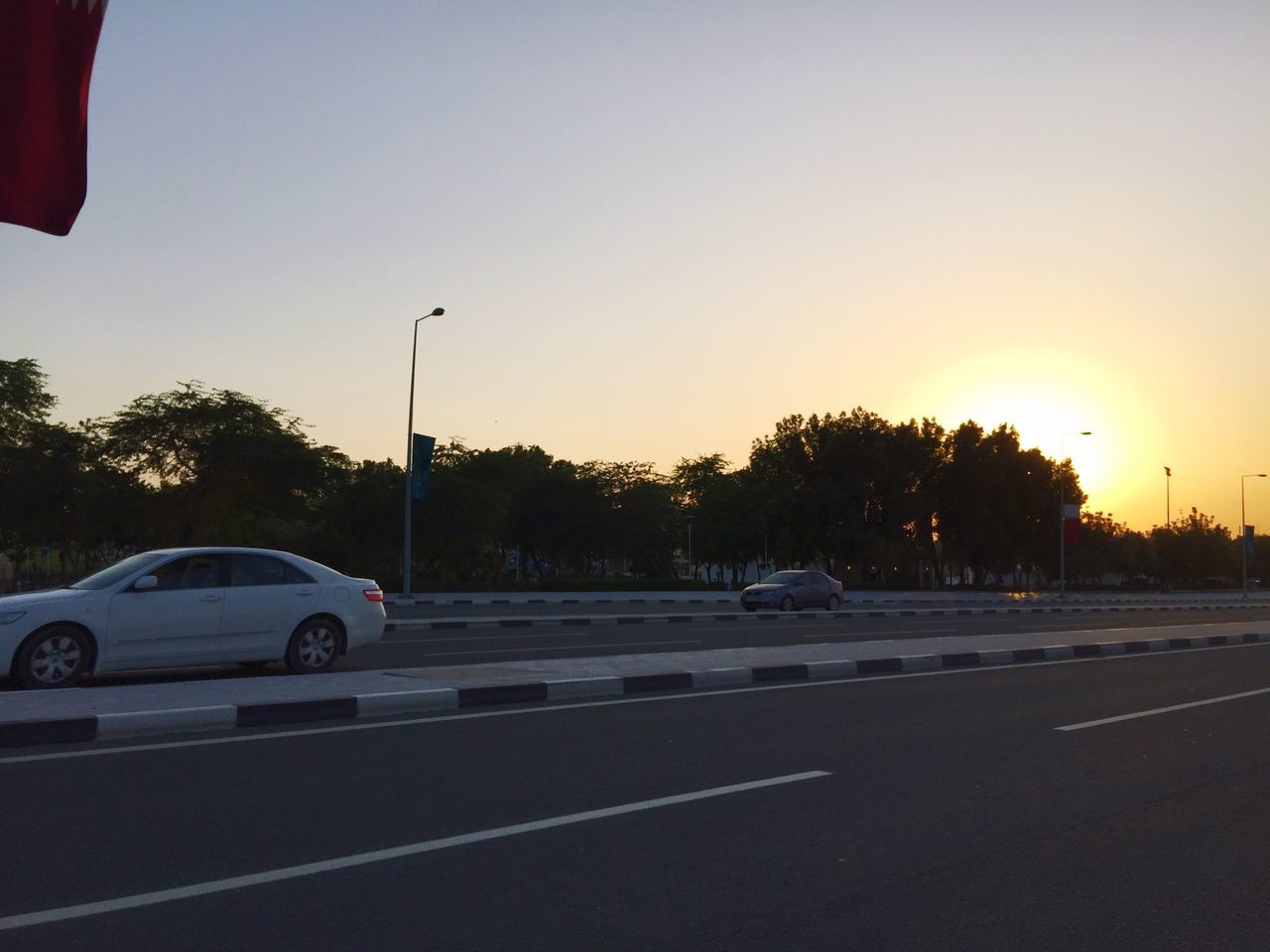 transportation, land vehicle, car, mode of transport, road, street, road marking, clear sky, sunset, on the move, tree, the way forward, travel, traffic, street light, copy space, sky, outdoors, stationary, sunlight