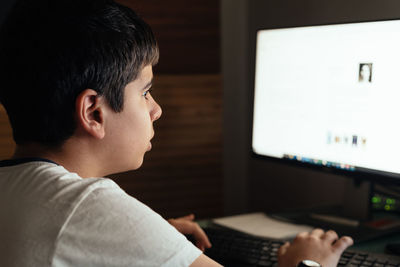 Side view of boy using computer at home