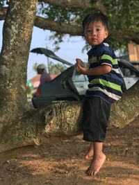 Portrait of happy boy playing on tree trunk