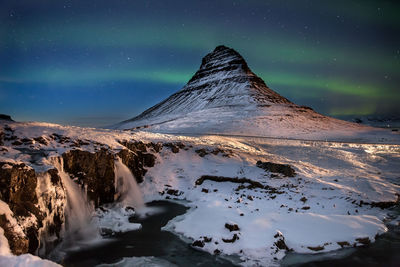 Scenic view of snowcapped mountain against sky during aurora borealis