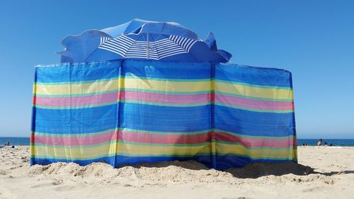 Close-up of multi colored umbrellas on beach against clear blue sky