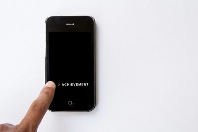 Close-up of hand holding smart phone over white background