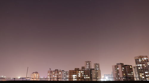 Illuminated buildings against clear sky at night