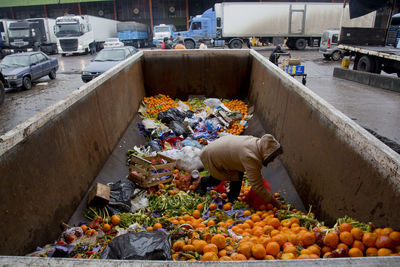 Woman rescuing good food from a garbage container 