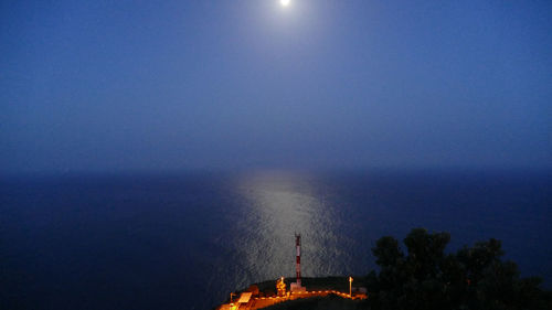 Illuminated sea against sky at night