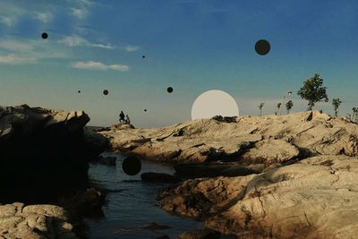 Hot air balloons flying over rocks against sky