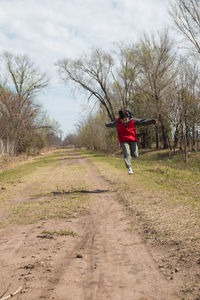 Full length of boy running on dirt road