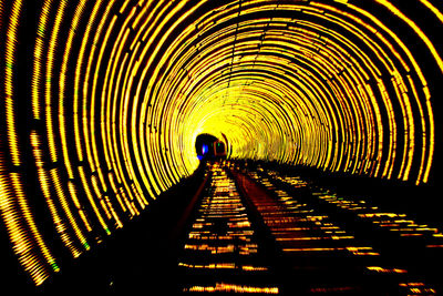 Silhouette person walking in illuminated tunnel