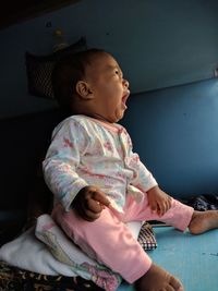 Cute baby girl yawning while looking away in train