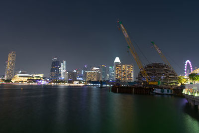 River by illuminated buildings against sky at night