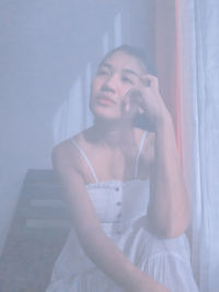 Young woman sitting by window at home