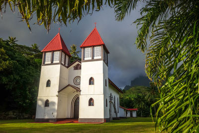 Built structure by trees and building against sky