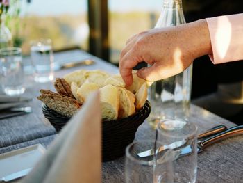 Cropped hand having bread at table in restaurant