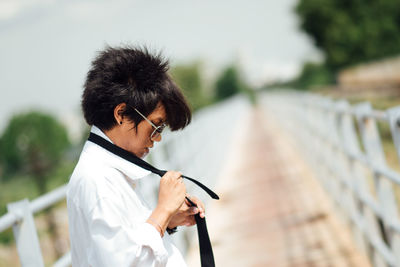 Businessman wearing necktie while standing on footbridge