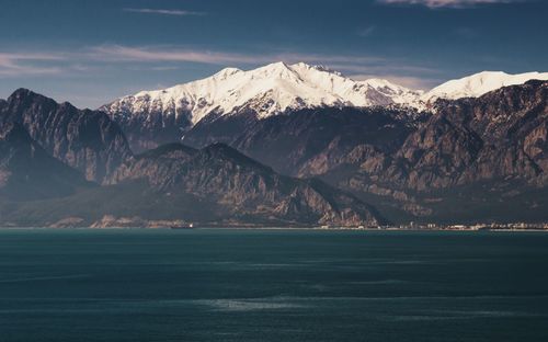 Scenic view of snowcapped mountains by sea against sky