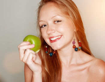 Portrait of young woman holding hair over white background