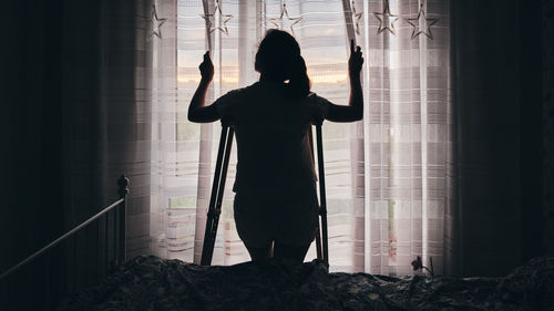 Rear view of woman standing by window