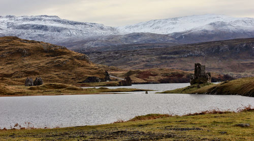 Scenic view of lake by snowcapped mountains against sky