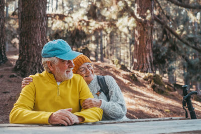 Side view of woman sitting on tree trunk in forest