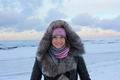 Portrait of young woman standing on snow covered field